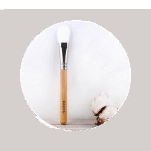 Pinceau masque visage avec une boule de coton sur un fond blanc