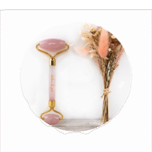 rouleau en jade pour visage de couleur rose avec un bouquet de fleur de couleur rose aussi