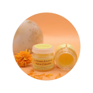 Baume à lèvre au calendula sur fond orange avec une pierre et une fleur orange